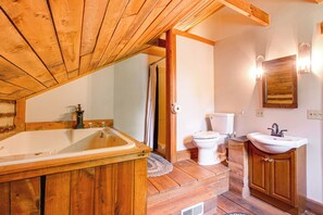 Un baño de madera con bañera, inodoro y lavamanos.