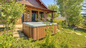 Eine rustikale Holzhütte mit Steinfassade, einer Holzterrasse und einem Whirlpool.