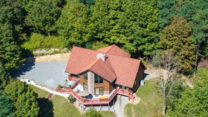 A large, single-story house with a red roof, surrounded by dense forest. - Deck & Mtn Views: Log Cabin By Snowshoe Mountain! (Valley Head)