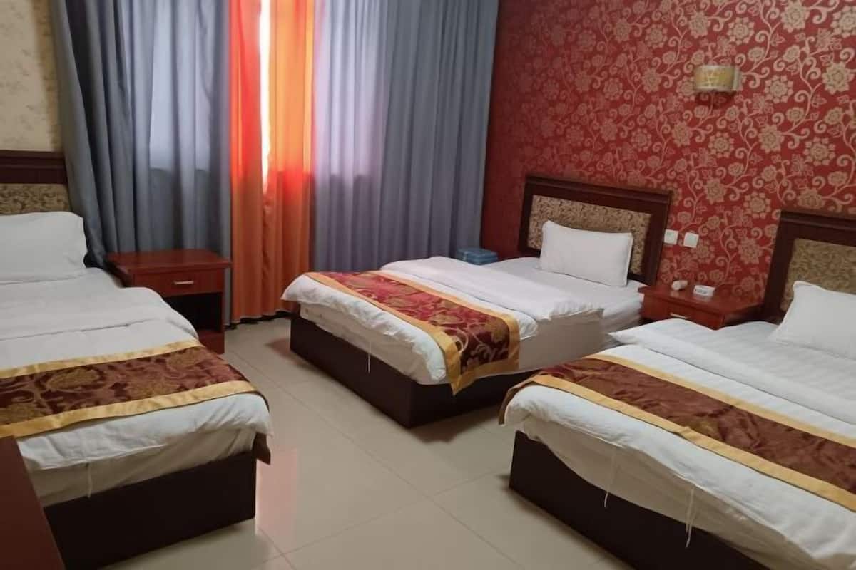 A hotel room with two beds, a nightstand, and a window with curtains.