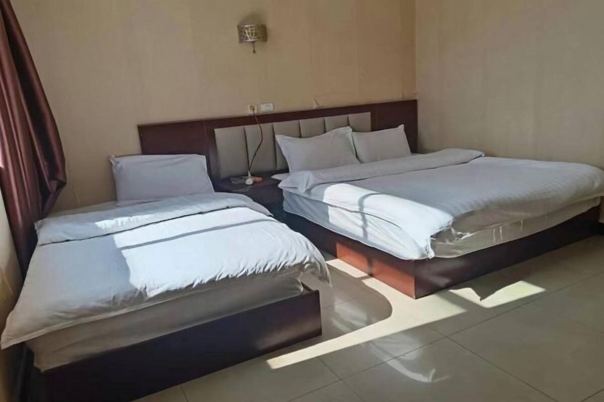 A hotel room with two beds, a wooden headboard, and a tiled floor.
