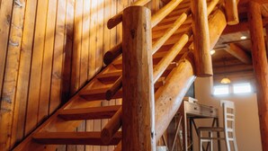 Una escalera de madera con barandilla, paredes de madera y una ventana.