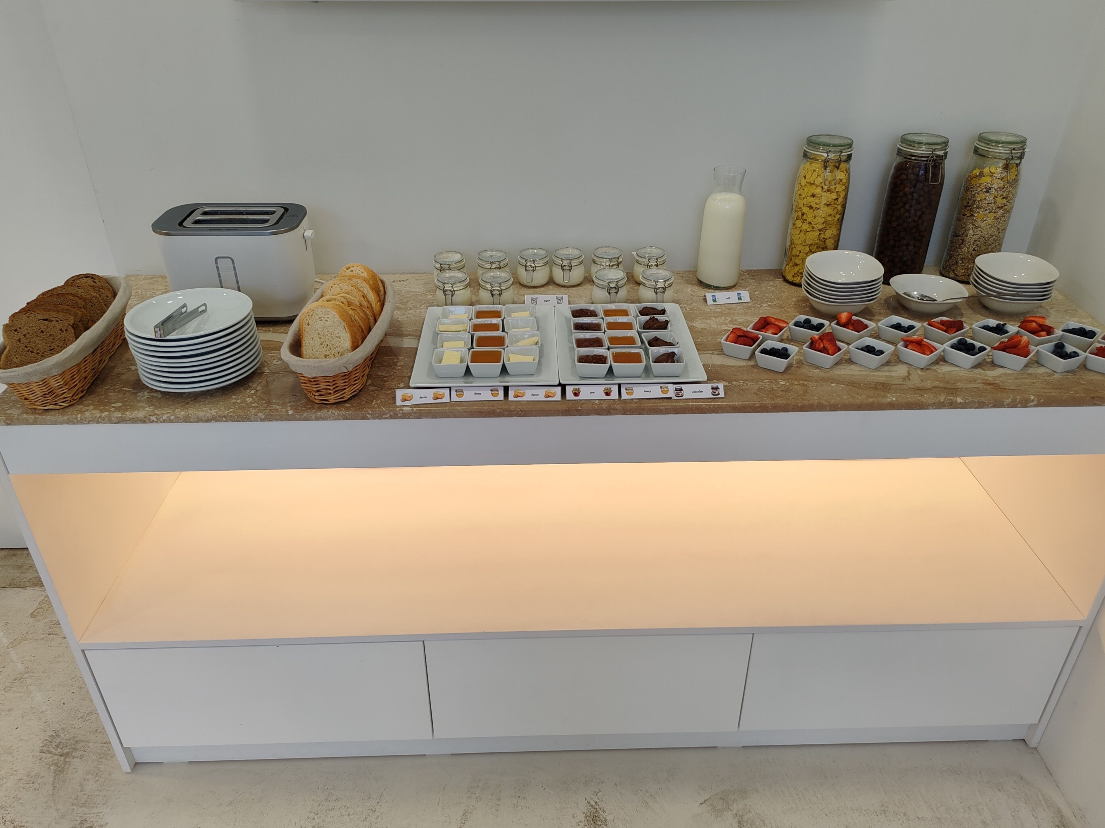 A buffet setup with bread, butter, jams, and fruits.