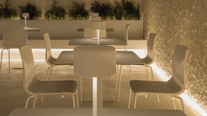 A modern indoor dining area with a central table, white chairs, and a textured wall. - Hotel Hello Plovdiv (Plovdiv)