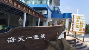 A wooden boat with the inscription "海天一色" in front of a building with blue and white colors. - Jiaoyi Seaview Hotel (Taishan)