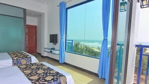 A hotel room with two beds, a TV, and a balcony with a view of the beach. - Jiaoyi Seaview Hotel (Taishan)