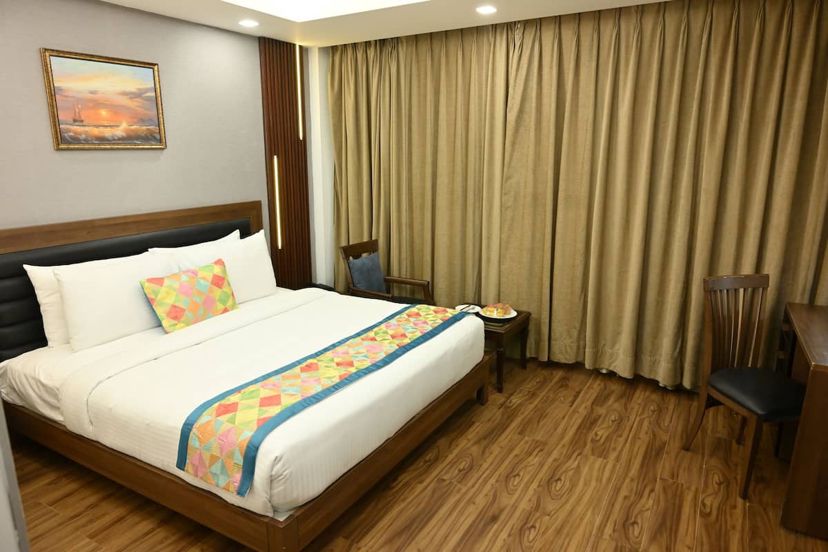A hotel room with a large bed, a wooden headboard, a nightstand, a chair, and a large window with curtains.