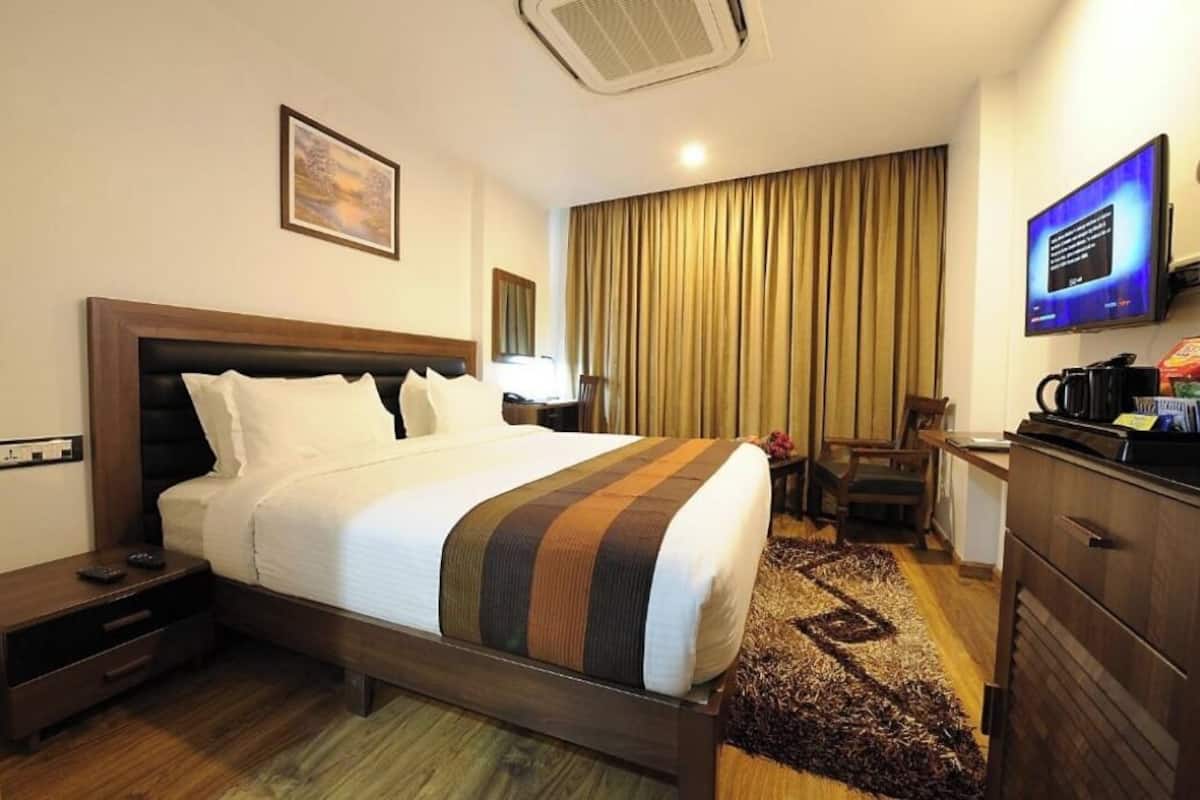 A hotel room with a bed, a desk, a television, and a coffee maker.