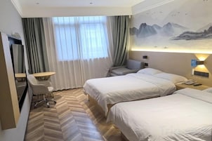 Habitación de hotel con dos camas, un escritorio, una silla y un televisor.