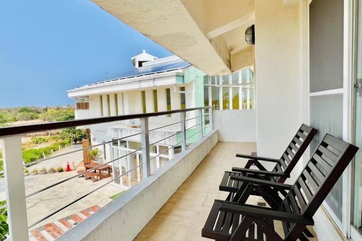 A balcony with a view of a building, a table, and chairs.