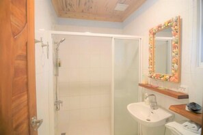 Une salle de bain équipée d’une douche, d’un lavabo et d’un miroir agrémenté d’un cadre décoratif.