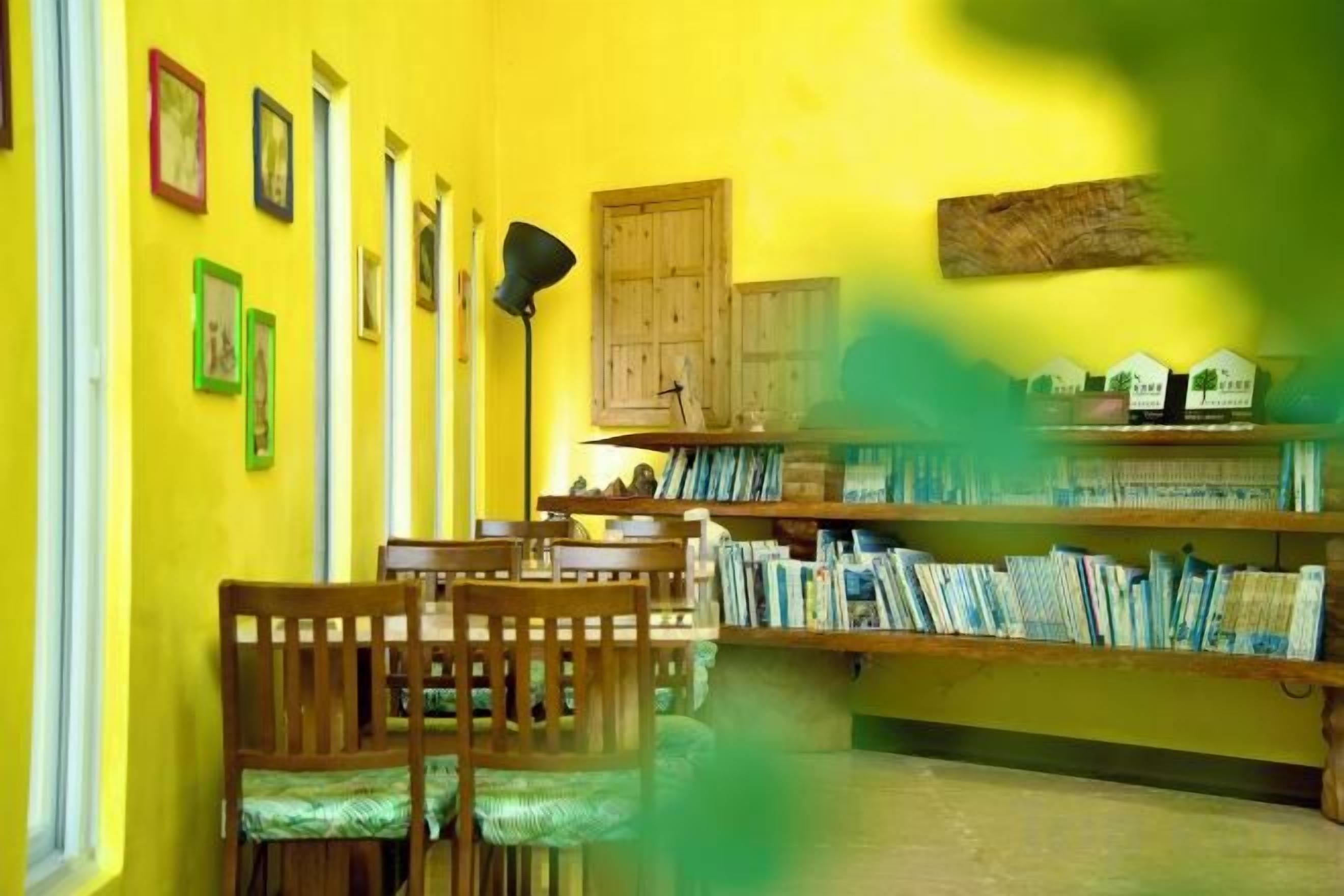 A room with a dining table, chairs, a bookshelf, and a door.