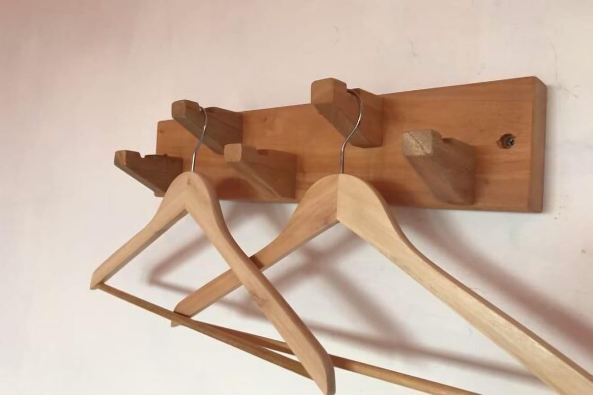 Un porte-manteau mural en bois, doté de trois patères en bois.