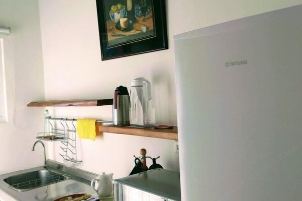 Une cuisine équipée d’un évier, d’une machine à café et d’un réfrigérateur.