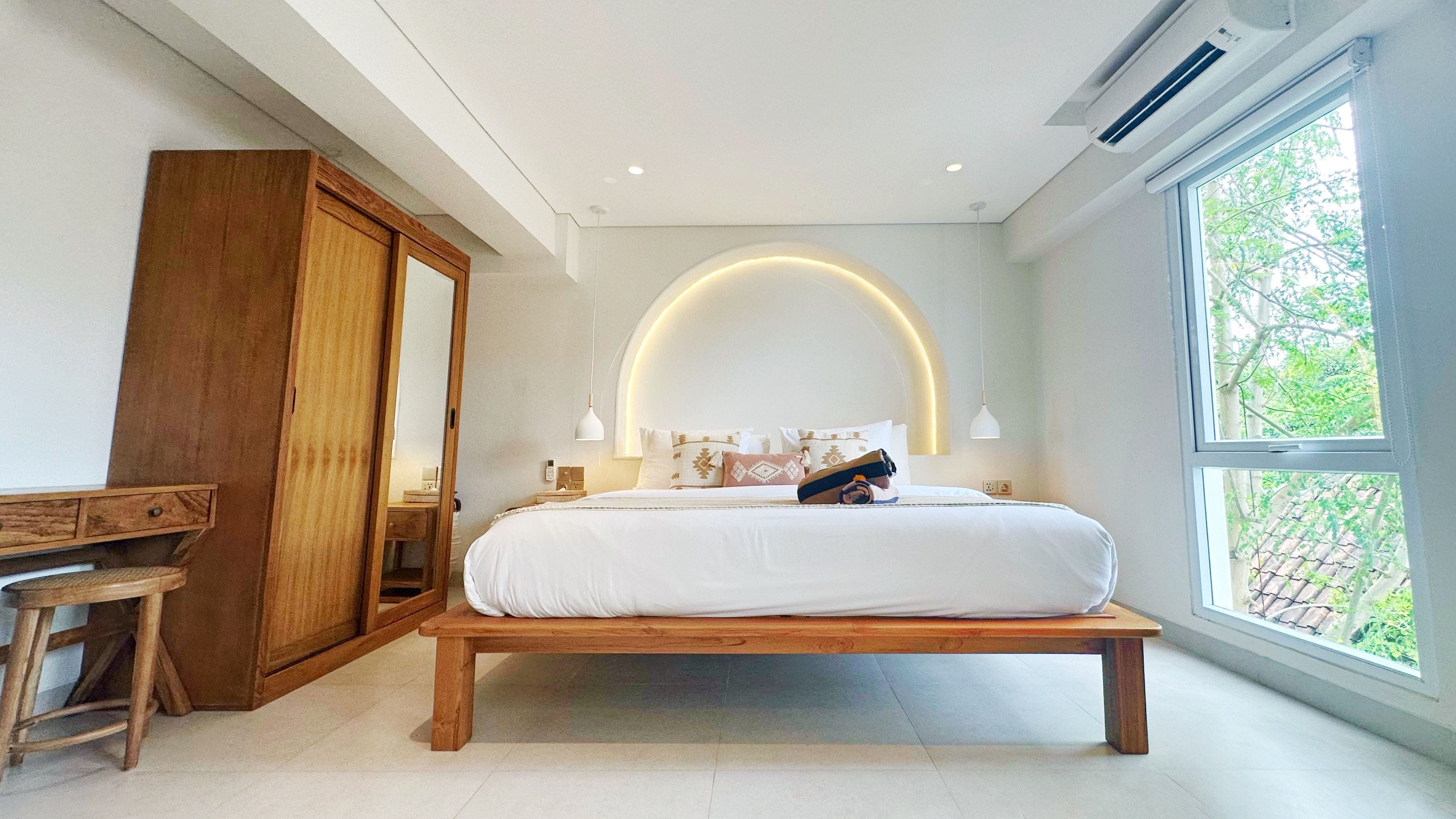 Ein Schlafzimmer mit einem Bett, einer Holzbank, einem Kleiderschrank und einem großen Fenster.