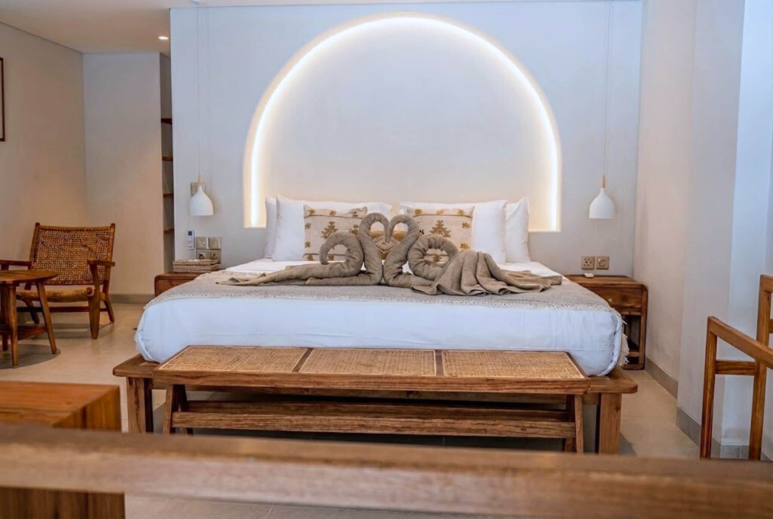 A modern bedroom with a large bed, wooden headboard, and bedside tables.