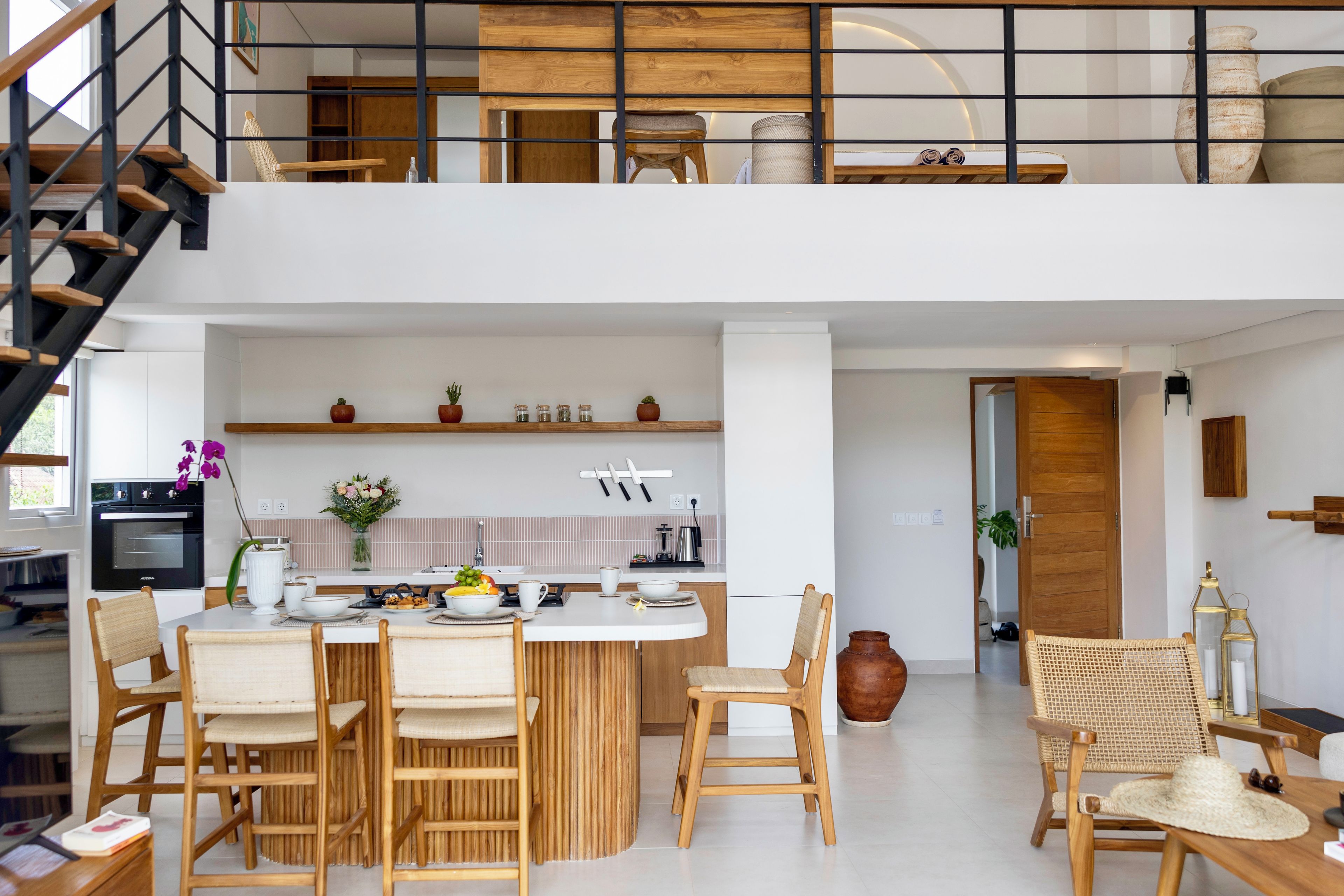 A modern kitchen with a dining area, wooden furniture, and a staircase.
