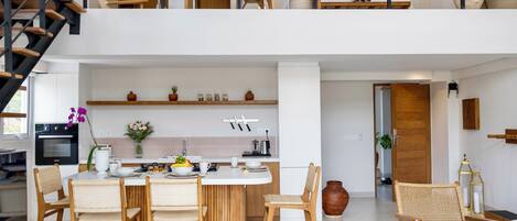A modern kitchen with a dining area, wooden furniture, and a staircase.