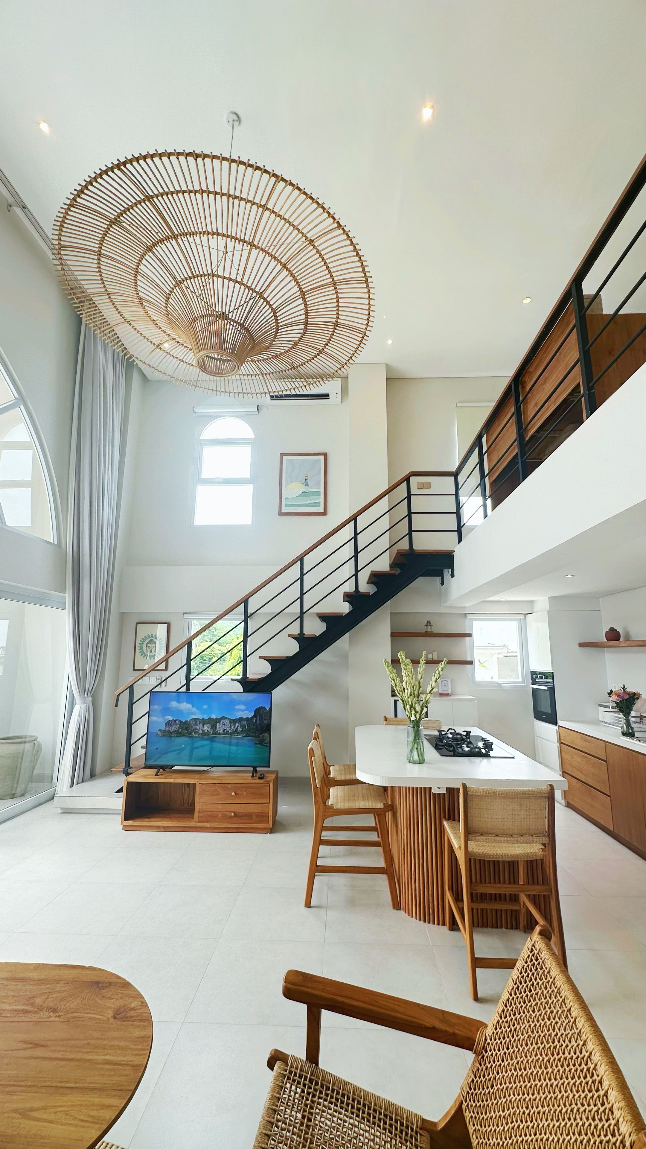 A spacious living area with a staircase, a dining table, and a large TV.