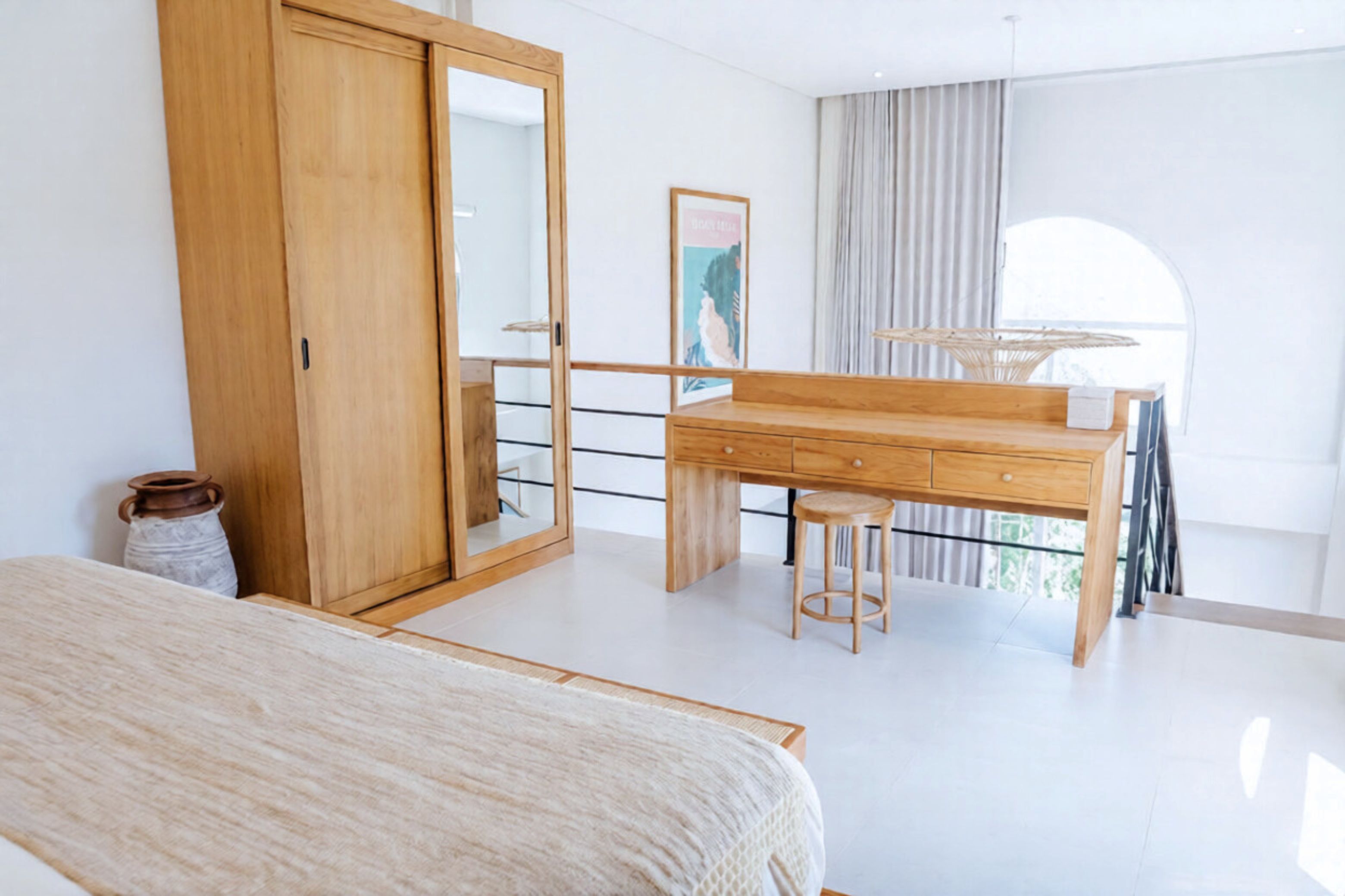 Une chambre moderne avec un grand lit, un bureau en bois, une chaise, une armoire et un balcon avec vue.