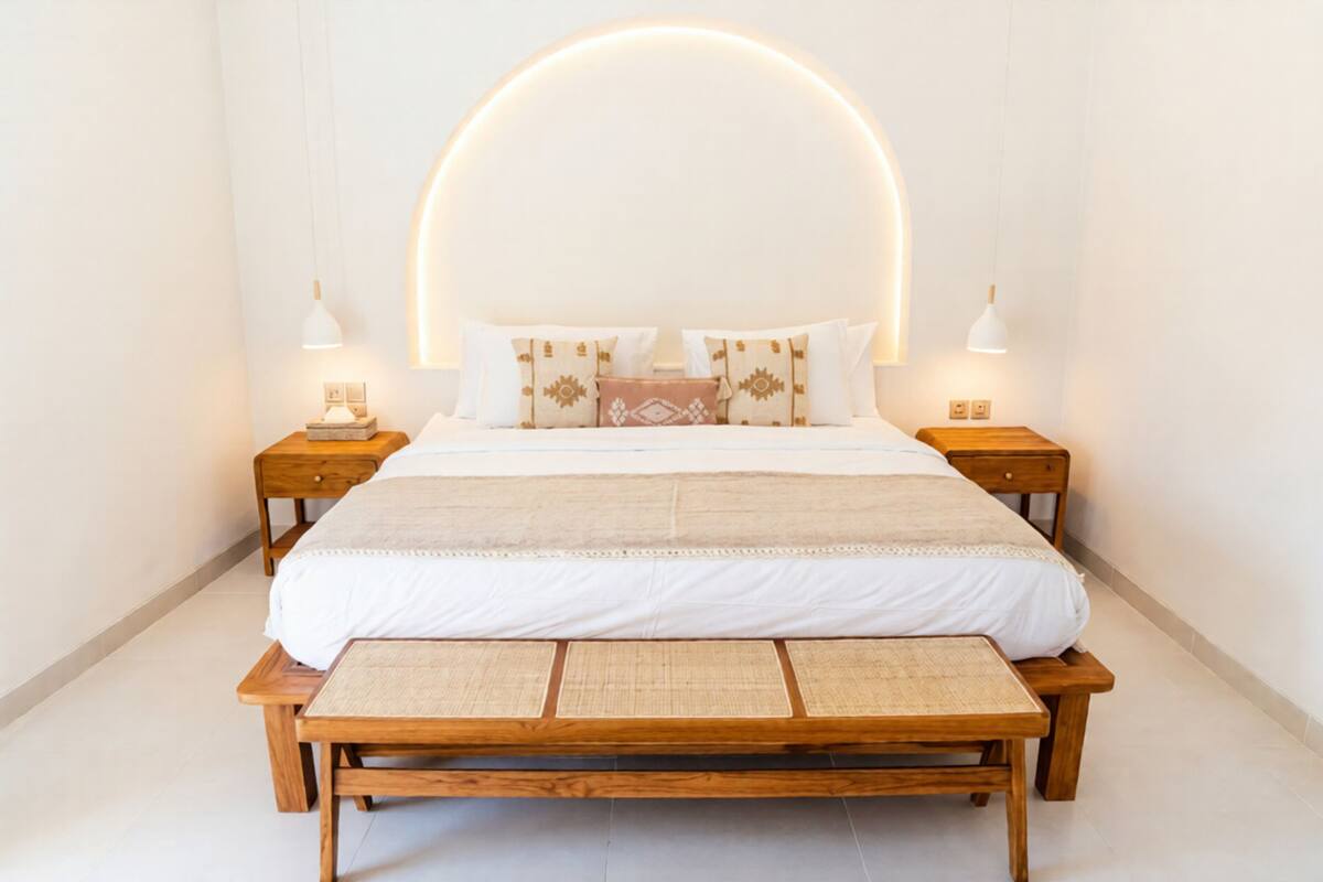 A neatly arranged bedroom with a large bed, bedside tables, and a bench.