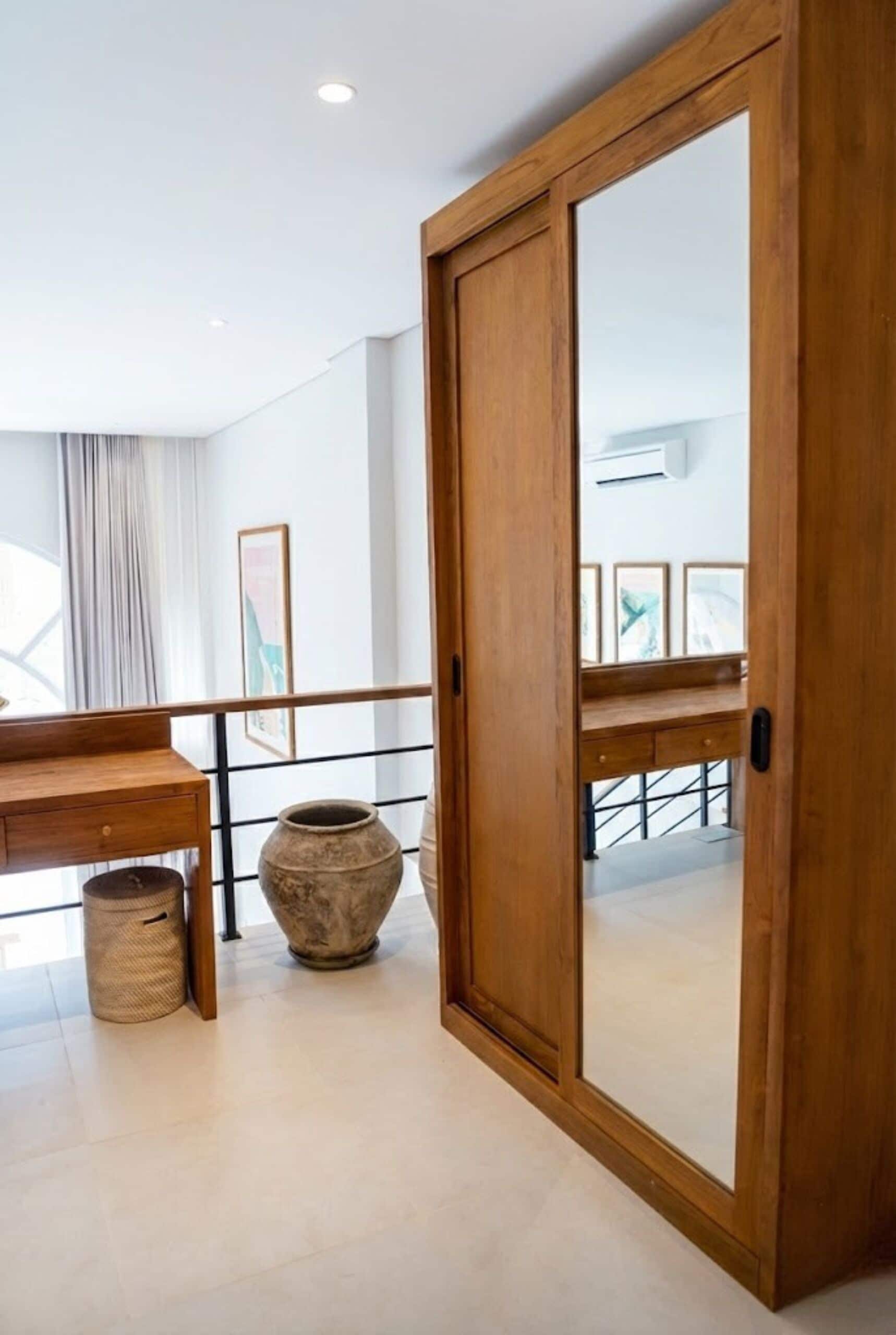 Ein Zimmer mit Holztür, Schreibtisch, einem gewebten Korb und einer großen Vase.