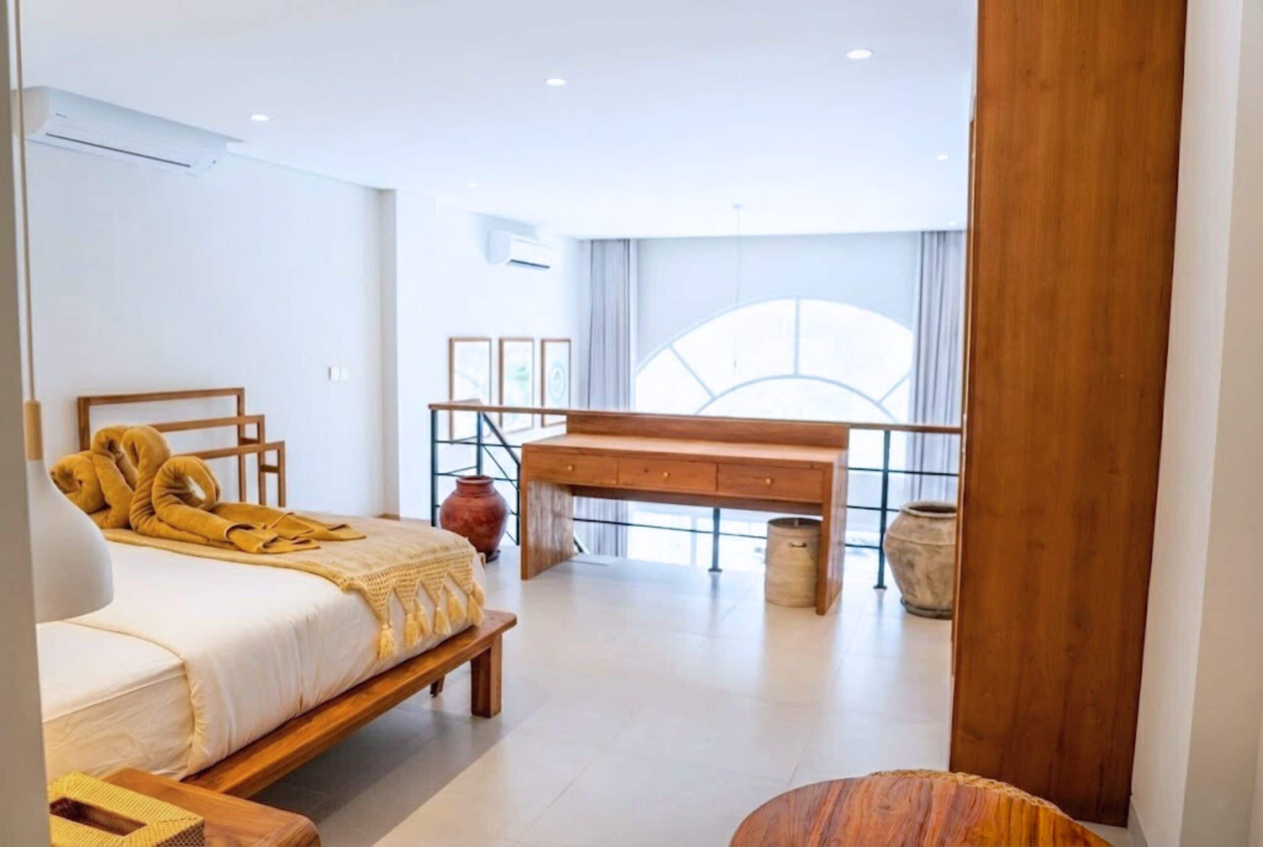 Ein modernes Schlafzimmer mit Bett, Schreibtisch aus Holz und einem großen Fenster.