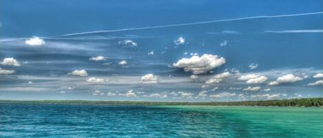 Un cielo azul despejado con nubes sobre un mar turquesa y una costa lejana.
