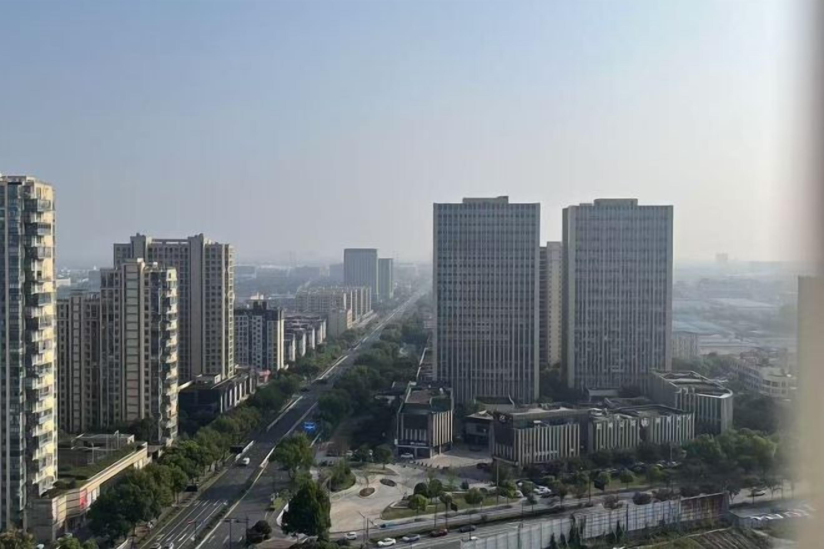 A high-rise urban area with multiple buildings, a clear sky, and a river in the foreground.