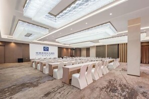 A conference room with a long table and chairs, a projector screen, and a large chandelier. - New Century Hotel (Tongxiang)