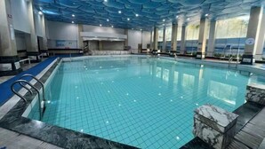 Μια εσωτερική πισίνα με πλακάκια στο δάπεδο και ένα ταβάνι με γεωμετρικό σχέδιο.