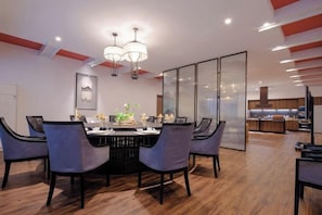 A modern dining area with a round table, chairs, and a chandelier. - New Century Hotel (Tongxiang)