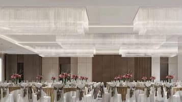 A banquet hall with round tables, white tablecloths, and gold sashes.