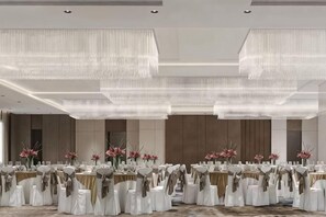 A banquet hall with round tables, white tablecloths, and gold sashes. - New Century Hotel (Tongxiang)
