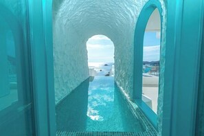 An arched glass tunnel leading to a pool with a clear view of the ocean and distant land. - Loccal Collection Hotel Komodo (Labuan Bajo)