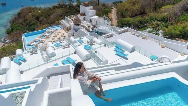 A rooftop pool area with lounge chairs and a person sitting by the pool. - Loccal Collection Hotel Komodo (Labuan Bajo)