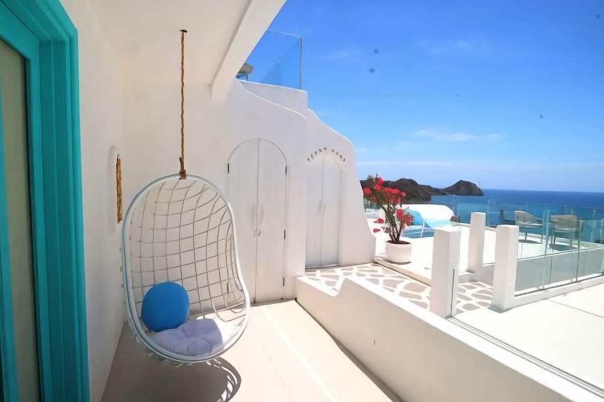Ein Balkon mit einer Hängematte, einer weißen Tür und Blick aufs Meer.