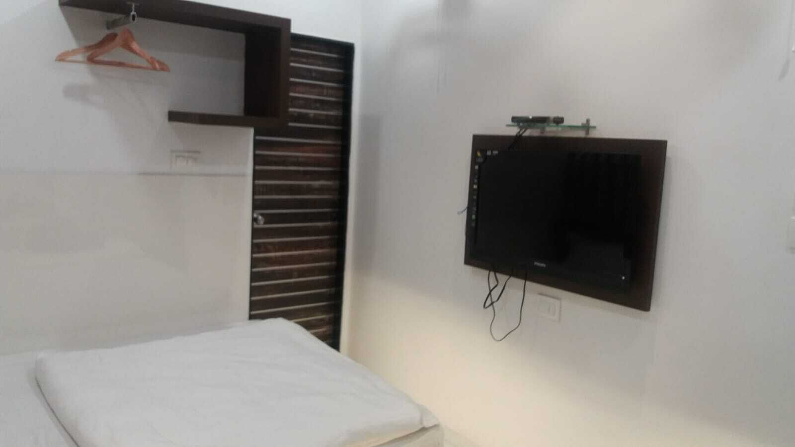 Un dormitorio con una cama, un televisor montado en la pared y un armario con puerta corredera.