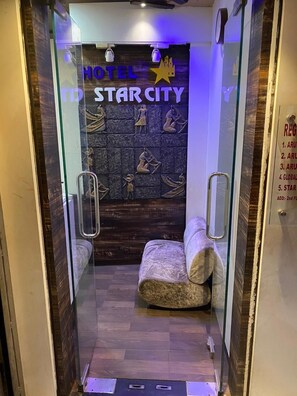 A hotel room with a glass door, a bed with patterned bedding, and a wall with Egyptian-themed artwork. - Hotel Star City (Kolkata)