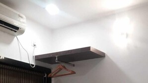A bedroom with a bed, a window with blinds, a radiator, and a wall-mounted shelf with a hanger. - Hotel Star City (Kolkata)