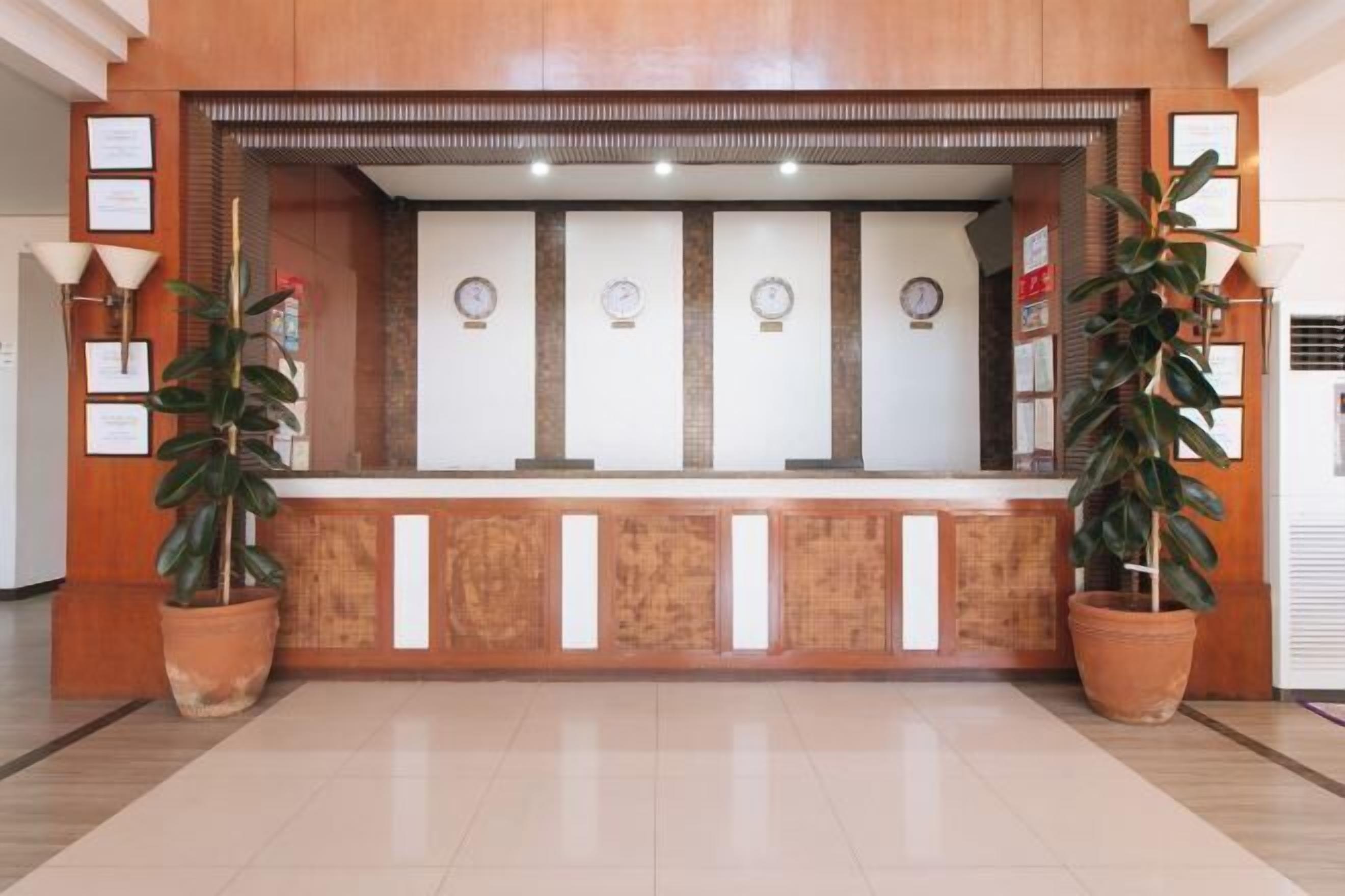 Un área de recepción con mostrador de madera, diplomas enmarcados y plantas en macetas.