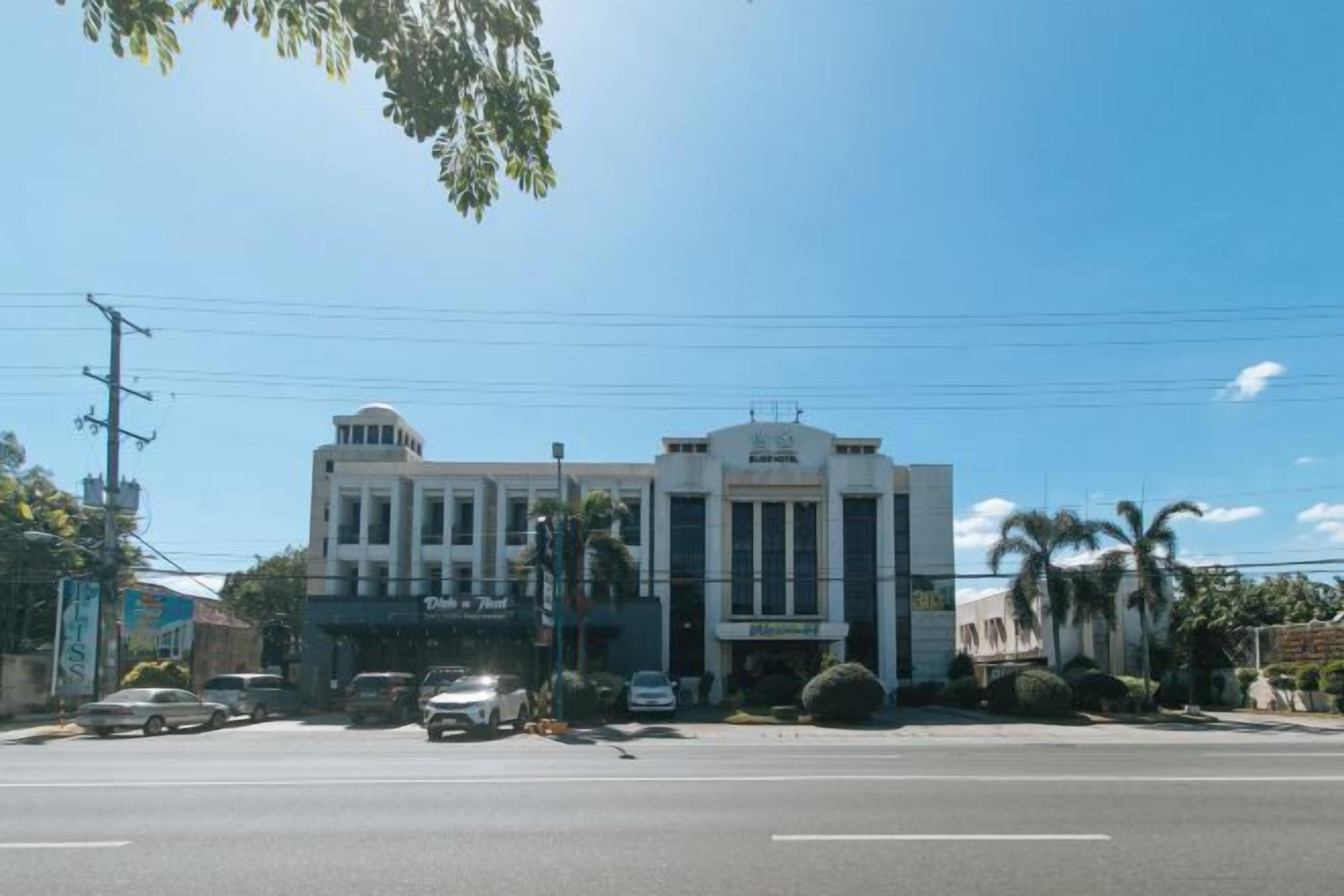 Un hotel de estilo arquitectónico clásico, con una entrada central que destaca por un amplio frente de vidrio y un diseño simétrico.