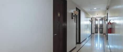 Pasillo de hotel con puertas, extintor y una lámpara.