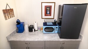 Eine kompakte Küchenzeile mit Mikrowelle, Toaster, Wasserkocher und kleinem Kühlschrank.