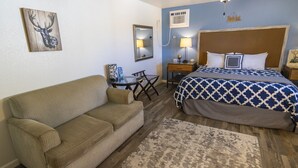 Ein Schlafzimmer mit Bett, Sofa, Schreibtisch, Stuhl und Teppich.