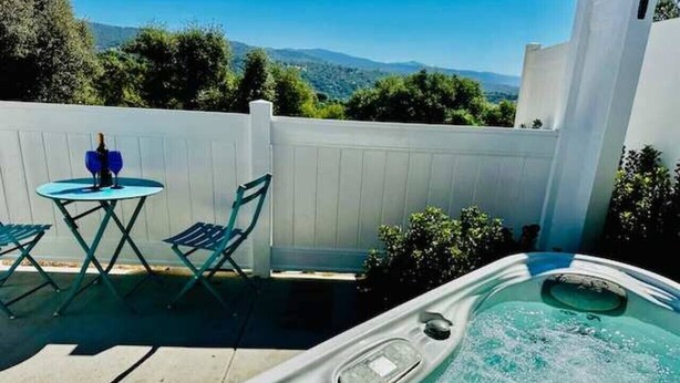 Ein Whirlpool mit Bergblick, ein weißer Zaun und ein Tisch mit Stühlen.