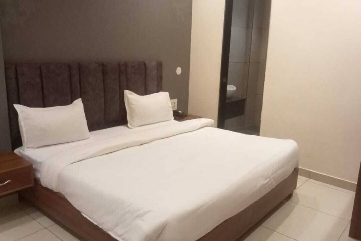 A neatly made bed with white linens in a hotel room.