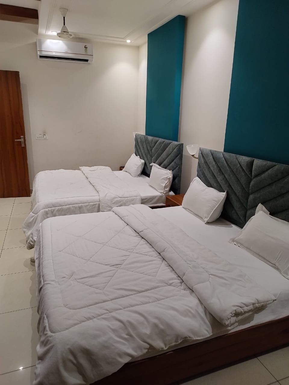 A hotel room with two beds, a ceiling fan, and an air conditioning unit.