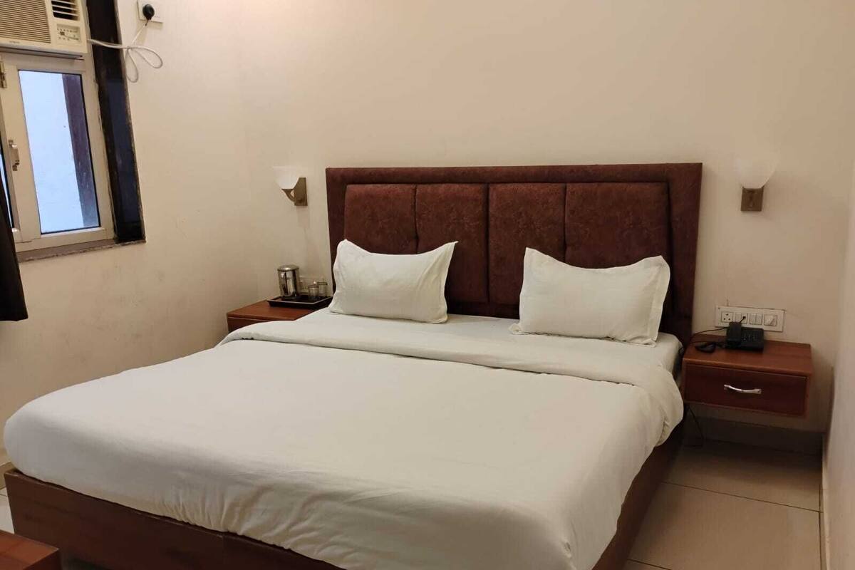 A neatly made bed with white linens in a hotel room.