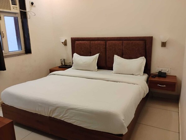 A neatly made bed with white linens in a hotel room. - HOTEL COMFORT INN BY GANGA GAURI HOTELS (Haridwar)